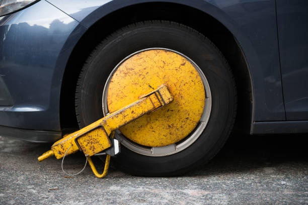 Metal parking boot installed on a vehicle front wheel which immobilizes the vehicle. 